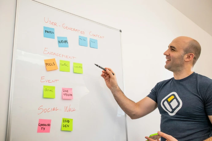 a man writing on a white board with sticky notes on it